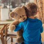 クマのぬいぐるみを抱く子供